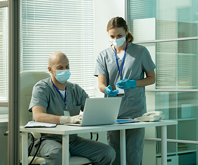 Two physicians are looking at the laptop