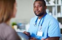 Doctor in scrubs talking to a patient and taking notes