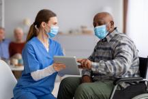 Female nurse helping black senior man