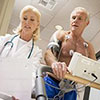 The doctor looking at the report with male patient having his monitoring device on.