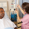 Male patient in hospital bed while nurse adjusts nearby instruments