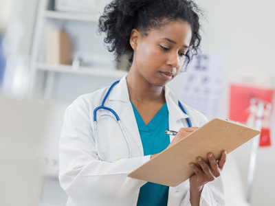 A doctor writes down information on a clipboard.